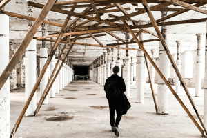 Man in a long hallway with beams above